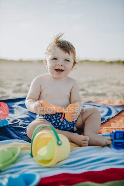 Bonito menino brincando com brinquedos na praia durante o pôr do sol — Fotografia de Stock