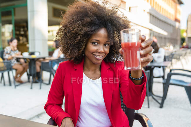 Mitte erwachsene Frau hält Saftglas in der Hand, während sie am Straßencafé sitzt — Stockfoto