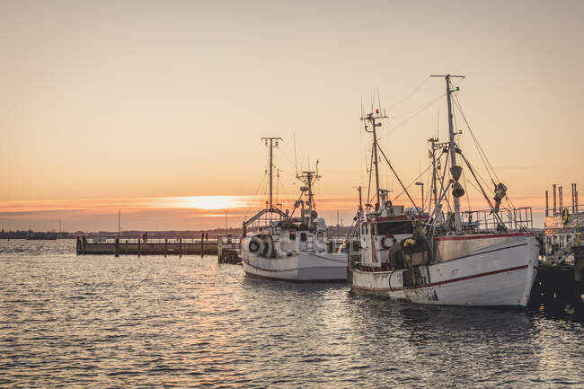 Germany, Schleswig-Holstein, Heikendorf, Fishing boats moored in harbor at sunset — Stock Photo