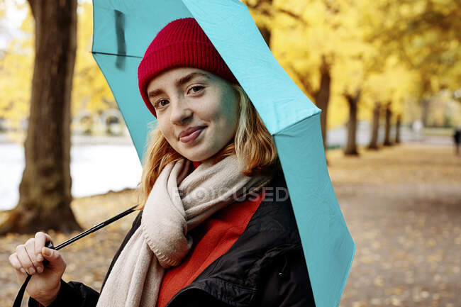 Красива дівчина-підліток тримає парасольку, стоячи в парку — стокове фото