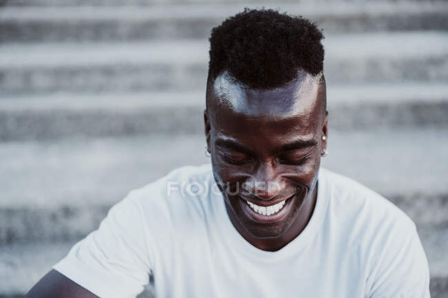 Sportsman ridere mentre seduto sulle scale all'aperto — Foto stock