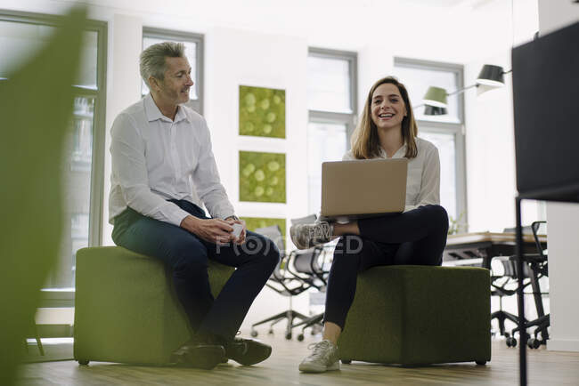 Smiling partners using laptop while sitting in office — Stock Photo