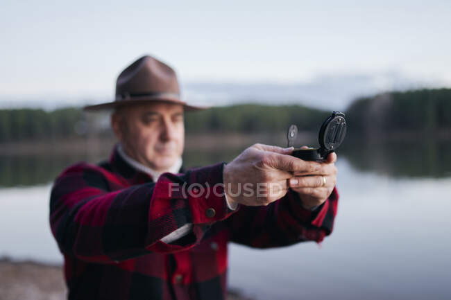 Bushcrafter hält beim Wandern im Wald Navigationskompass in der Hand — Stockfoto