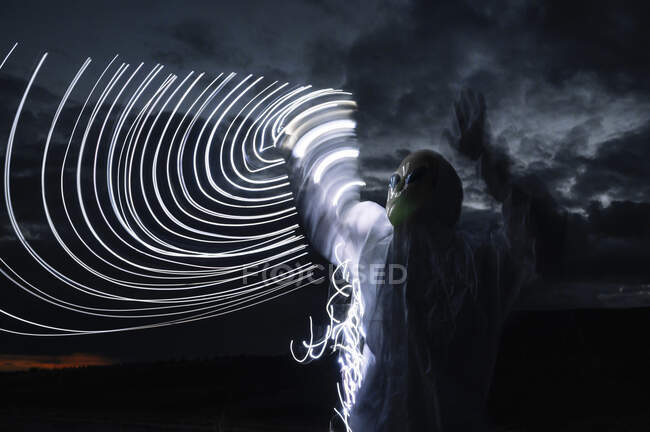 Alien standing by semi-circle light trails against sky at night — Stock Photo
