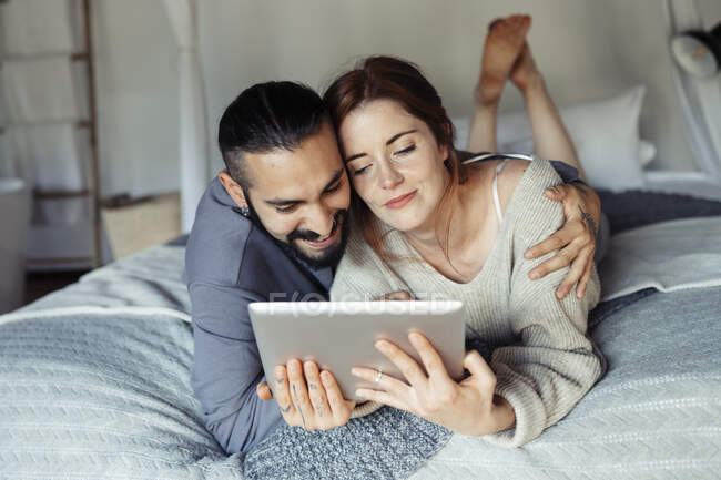Homem abraçando mulher ao usar tablet digital em casa — Fotografia de Stock