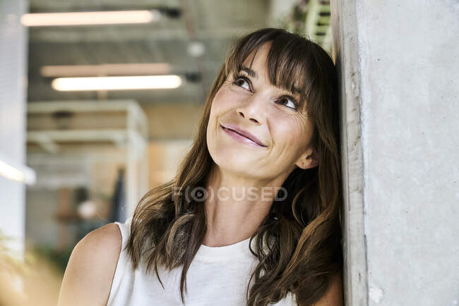 Woman looking up while leaning on wall at home — Foto stock