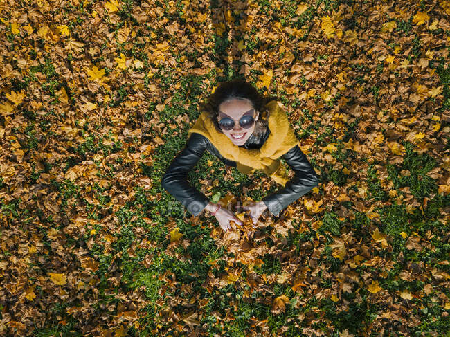 Donna felice che tiene le foglie secche mentre si gode al parco durante l'autunno — Foto stock