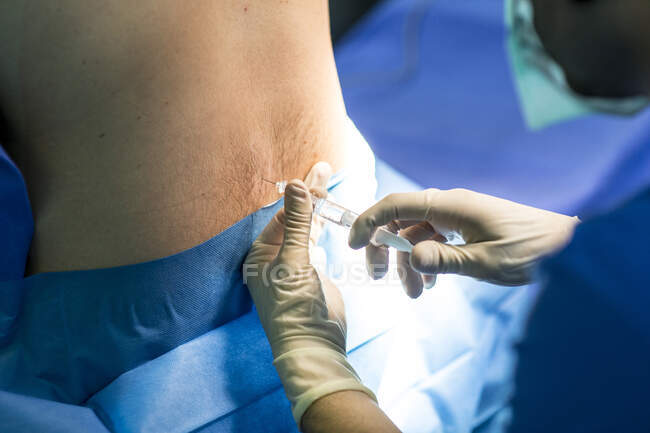 Мужчина-хирург, вводящий пациенту инъекции в операционную в больнице — стоковое фото