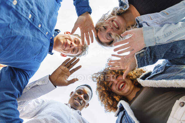 Lächelnde Freundinnen und Freunde winken mit den Händen — Stockfoto