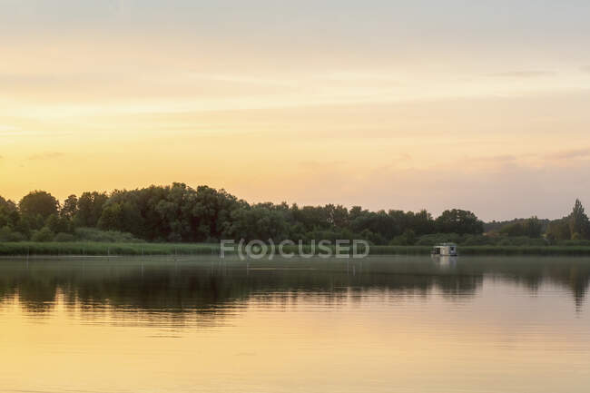 Vista a distanza della casa galleggiante nel lago durante il tramonto — Foto stock