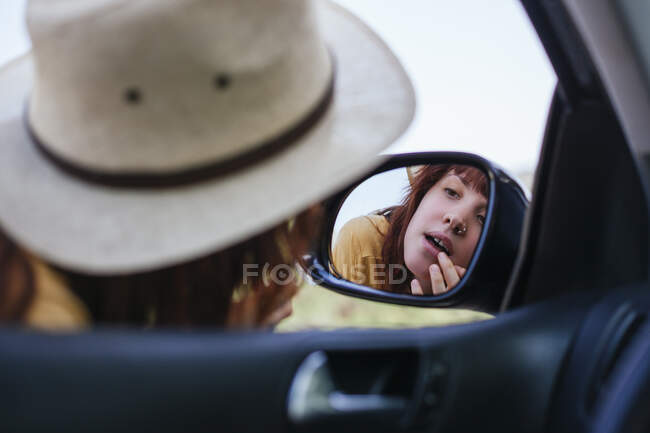 Frau blickt auf Selbstreflexion im Seitenspiegel — Stockfoto