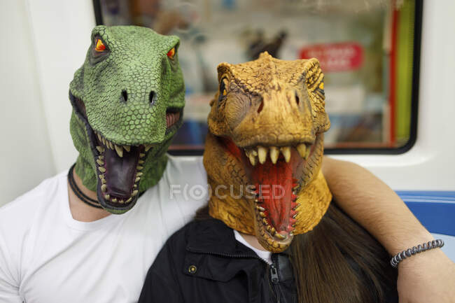 Hombre y mujer con máscara de dinosaurio mientras viajan en tren - foto de stock