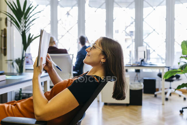 Sorridente donna d'affari che legge il diario in ufficio — Foto stock