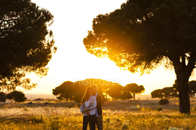 Romantic young couple standing on agricultural field against during sunset — Stock Photo
