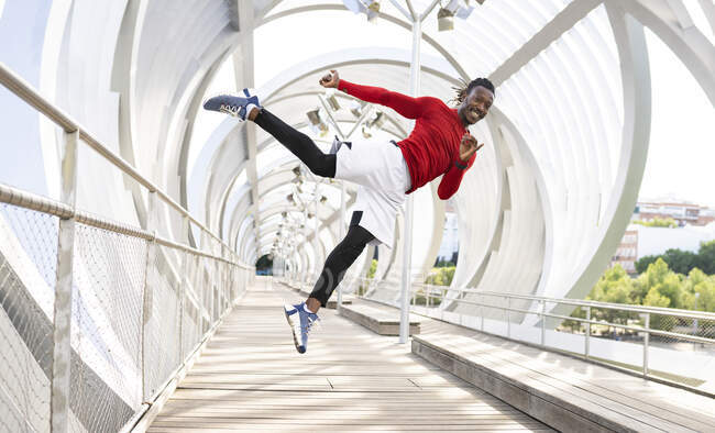 Male sportsman smiling while jumping on walkway — Stock Photo