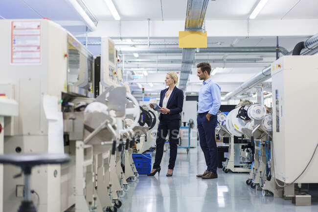 Male technician standing near businesswoman analyzing machinery at factory — Stock Photo