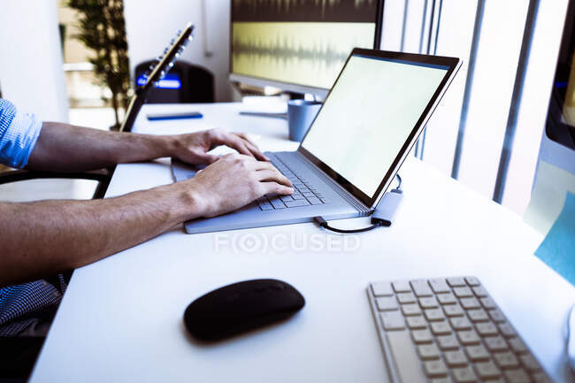 Profesional usando portátil mientras está sentado en el escritorio en el estudio - foto de stock