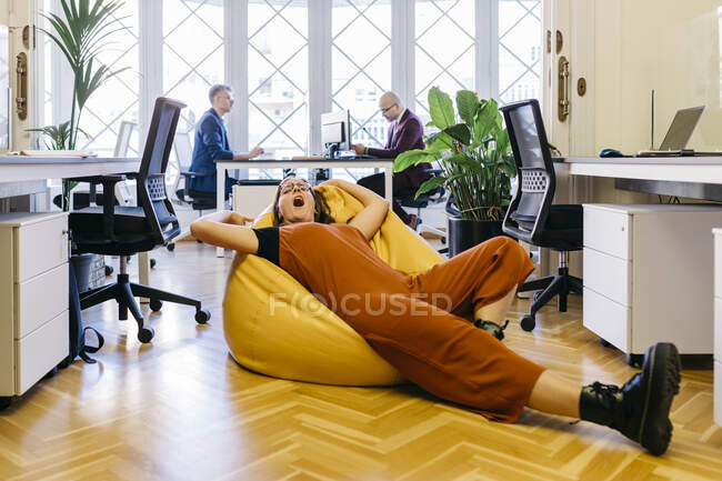 Erschöpfte Geschäftsfrau ruht im Büro auf Bohnensack — Stockfoto