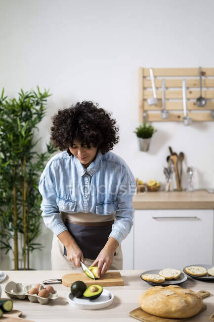 Mujer joven preparando sándwiches veganos en la cocina - foto de stock