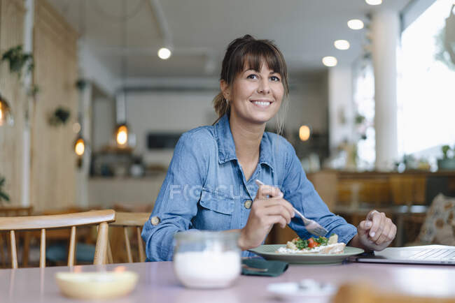 Женщина-владелец ест еду, сидя в кафе — стоковое фото