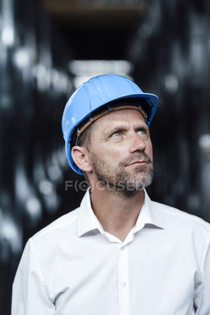 Businessman looking up while wearing hardhat at factory — Stock Photo
