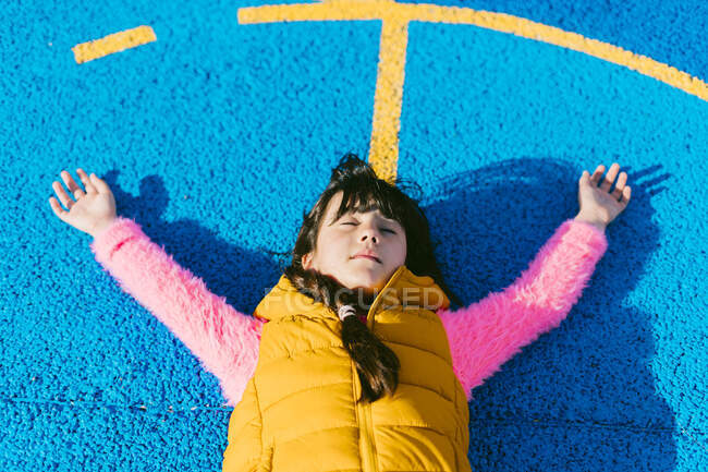 Chica relajante con los brazos levantados en la cancha de baloncesto - foto de stock