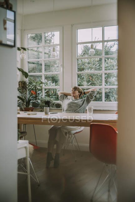 Mitte erwachsene Frau mit Händen hinter der Kopfstütze zu Hause — Stockfoto