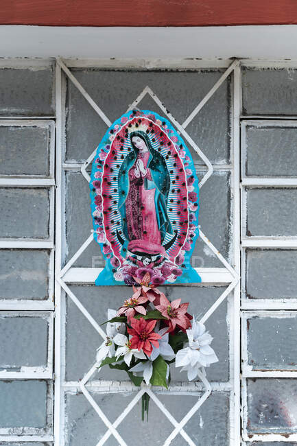 Figurine Vierge Marie avec des fleurs sur la grille métallique — Photo de stock