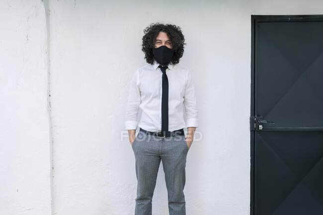 Geschäftsmann mit Mundschutz und Händen in Taschen, die gegen die Wand stehen — Stockfoto