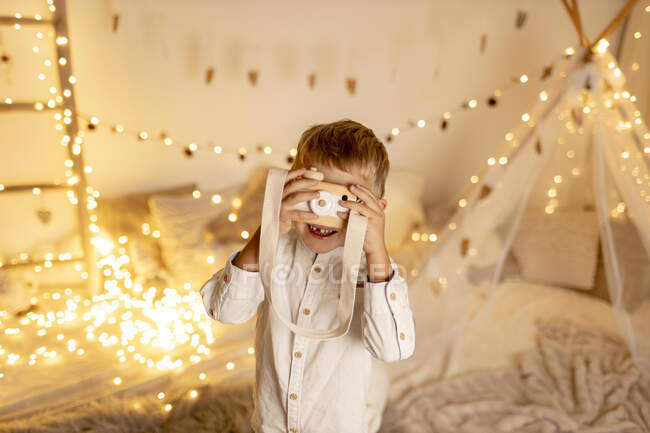 Carino biondo ragazzo giocare con giocattolo fotocamera in camera — Foto stock