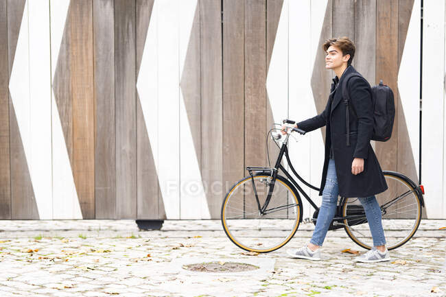 Giovane sorridente con zaino che cammina in bicicletta sul sentiero — Foto stock