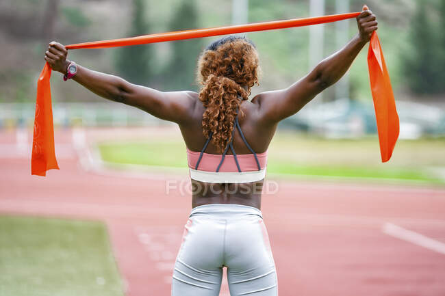 Sportswoman elastico banda di resistenza mentre in piedi sulla pista di corsa — Foto stock