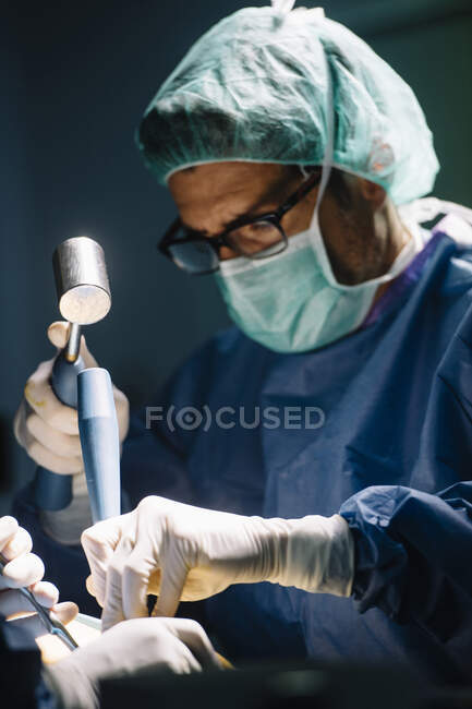 Чоловічий хірург за допомогою молотка робить операцію на щиколотці в операційній. — стокове фото