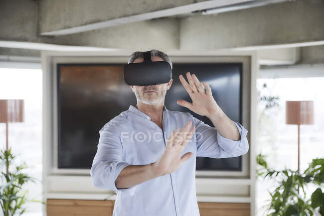 Businessman wearing virtual reality headset standing at home — Stock Photo