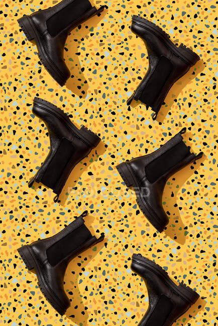Black leather boots on yellow terrazzo pattern — Stock Photo
