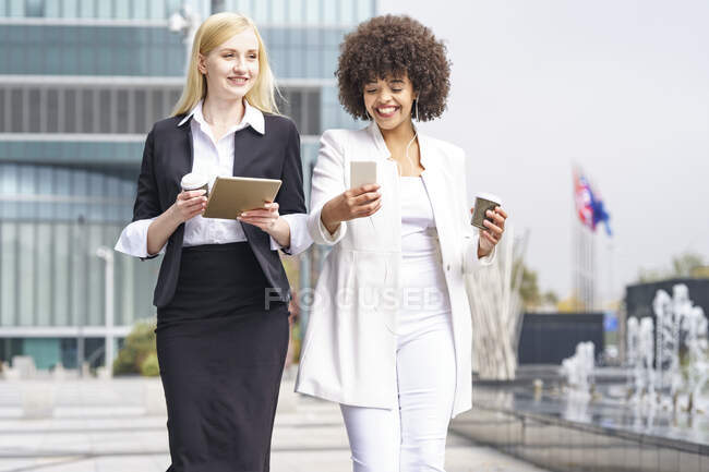 Geschäftsfrauen nutzen digitales Tablet und Smartphone, während sie gegen Gebäude stehen — Stockfoto