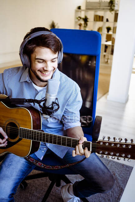 Smiling musician recording music while playing guitar at recording studio — Stock Photo
