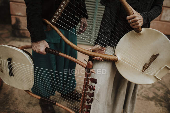 Male and female holding lyra musical instrument outdoors — Stock Photo