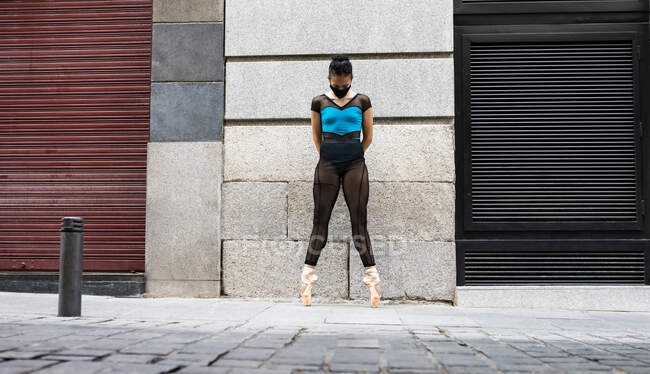 Danseuse de ballet portant un masque protecteur debout sur la pointe des pieds avec les mains derrière la tête sur le sentier pendant la COVID-19 — Photo de stock
