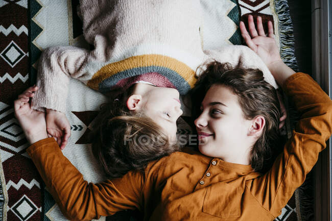 Sisters looking at each other while lying on blanket at home — Stock Photo