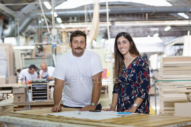 Project manager and architect discussing standing with coworker working in background at factory — Stock Photo