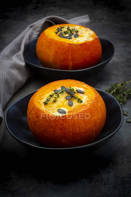 Studio shot of two Hokkaido pumpkins stuffed with camembert cheese, thyme and pumpkin seeds — Stock Photo