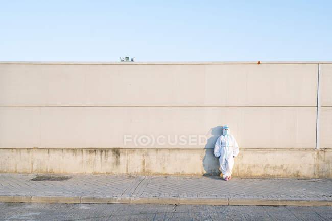Nurse wearing protective suit standing on footpath against wall — Stock Photo