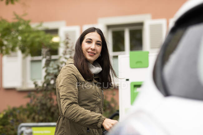 Smiling beautiful woman at electric vehicle renting station — Stock Photo
