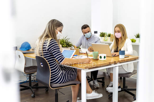 Деловые люди в маске, сидя за столом в офисе — стоковое фото
