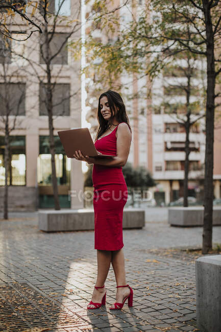 Empresária usando laptop enquanto está em pé no caminho da cidade — Fotografia de Stock