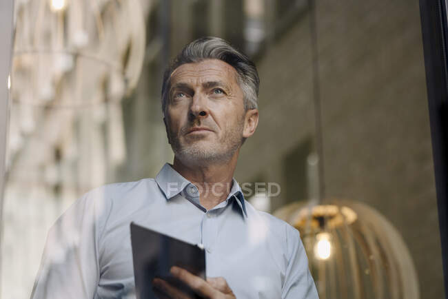 Mann benutzt digitales Tablet im Büro an Glaswand — Stockfoto