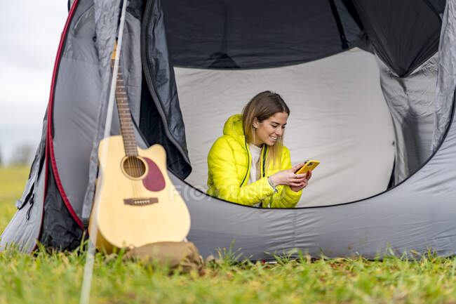 Junge Frau benutzt Smartphone im Zelt — Stockfoto