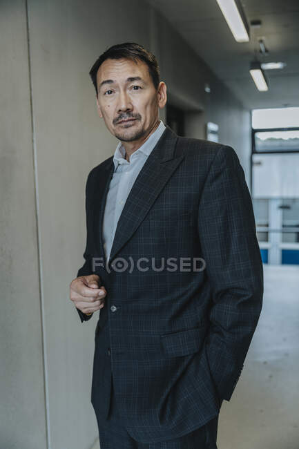 Businessman with hands in pockets standing at laboratory corridor — Stock Photo