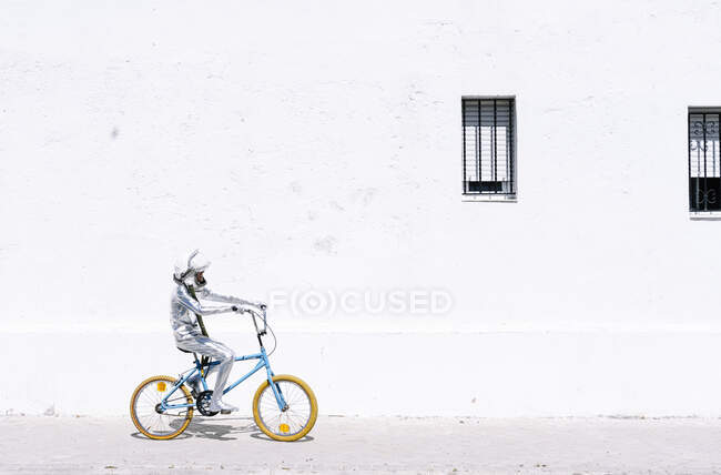 Грайливий хлопчик в астронавті їздить на велосипеді проти стіни. — стокове фото